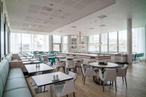 a restaurant with tables and chairs and large windows at Radisson RED, Oslo Airport in Gardermoen