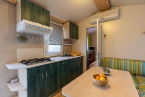 a kitchen with green cabinets and a bowl of fruit on a table at Hiška pod Rudnico 2 in Podčetrtek