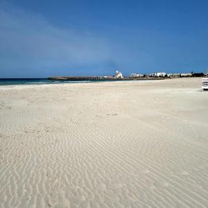 a sandy beach with a bench sitting on top of it at Sabbia e Mare in Torre San Giovanni Ugento