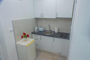 una cocina con armarios blancos, fregadero y flores en Apartments KOVAC en Tivat