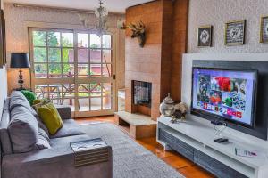 a living room with a couch and a flat screen tv at LOCAR-IN GRAMADO - Apartamento Rua Torta in Gramado