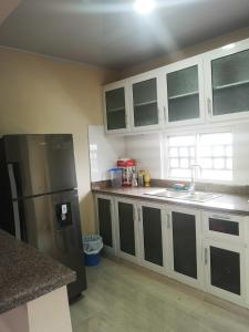 eine Küche mit weißen Schränken und einem schwarzen Kühlschrank in der Unterkunft pié de la montaña 2 in Bonao