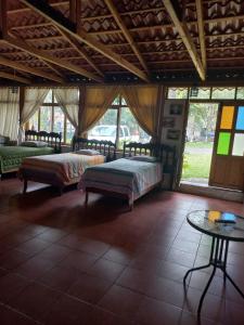 a bedroom with two beds and a table and windows at Hotel y Bungalows ecologicos Marcelo in Santiago Atitlán