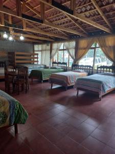 a room with four beds and a table and chairs at Hotel y Bungalows ecologicos Marcelo in Santiago Atitlán