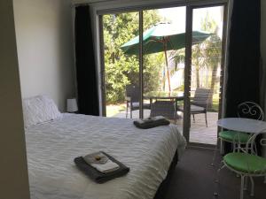 a bedroom with a bed and a patio with an umbrella at Jennie's In Whitianga in Whitianga