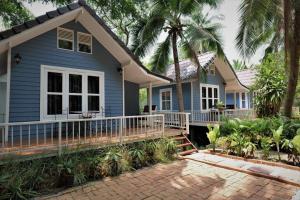 une maison bleue avec une véranda et des palmiers dans l'établissement Young Coconut Garden Home Resort, à Amphawa