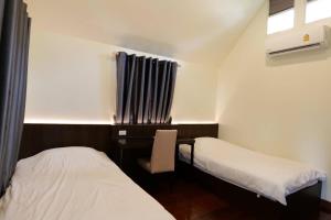 um quarto com 2 camas e uma secretária com uma janela em Young Coconut Garden Home Resort em Amphawa