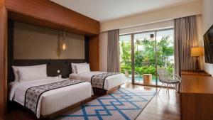a hotel room with two beds and a balcony at MERUSAKA Nusa Dua in Nusa Dua