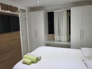 una camera da letto con un letto bianco con due asciugamani sopra di Apartamento a beira mar a João Pessoa