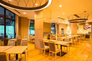 un restaurant avec des tables et des chaises en bois ainsi que des fenêtres dans l'établissement Blue Ridge Hotel, à Toyooka