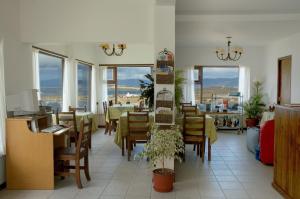 a dining room with a table and chairs and windows at Hosteria Sloggett in Ushuaia