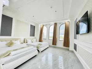 two beds in a white room with windows at Linh Phuong 6 Hotel in Can Tho