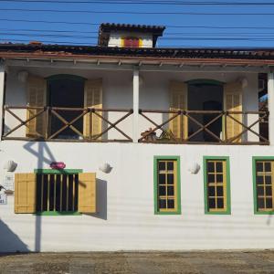 a white house with green windows and a balcony at Pousada Florescer in Paraty