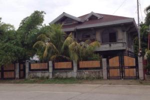 una casa antigua con una valla y palmeras en RedDoorz Hostel @ Madrias Pension House Isabela, en Tumauini