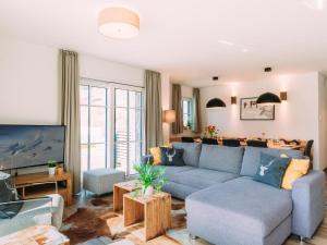 uma sala de estar com um sofá azul e uma televisão em Tauern Lodge XL em Piesendorf