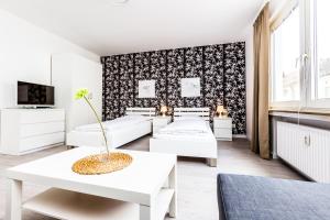 um quarto branco com duas camas e uma mesa em Cityfair Apartments Köln em Colônia