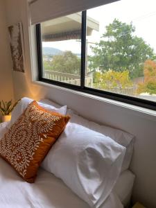a bed with a pillow sitting next to a window at Sea Renity in Safety Beach