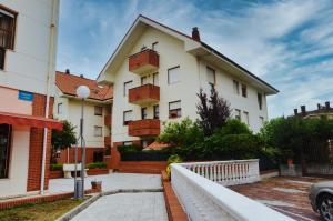 a white building with a fence in front of it at Apartamento Playas de Quejo in Isla