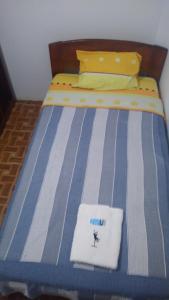 a bed with a blue and white striped comforter at BACHÍG Hospedaje in Moyobamba