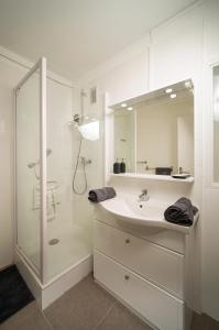 La salle de bains blanche est pourvue d'une douche et d'un lavabo. dans l'établissement Appartement tout équipé parking balcon 2 chambres, à Marseille