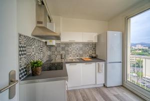 une cuisine avec un réfrigérateur blanc et une fenêtre dans l'établissement Appartement tout équipé parking balcon 2 chambres, à Marseille