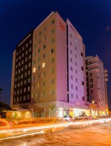 a tall white building with cars parked in front of it at Express Vieiralves in Manaus