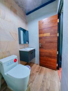 a bathroom with a toilet and a sink and a wooden door at SkyHome Wat JD I- Khai Resort & Restaurant in Ban Wat Boek