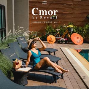 een vrouw op een stoel voor een zwembad bij Cmor by Recall Hotels SHA Extra Plus in Chiang Mai