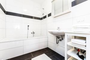 uma casa de banho branca com um lavatório e uma banheira em Cityfair Apartments Köln em Colônia
