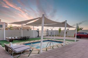 a white canopy over a pool with a table and chairs at Lazeemah Chalet استراحة اللزيمه in Ras al Khaimah