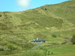 una casa al lado de una colina con un camino en Mountainview B&B, en Leenaun