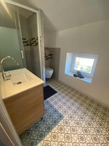 een badkamer met een wastafel, een toilet en een raam bij Douceur occitane in Saint-Chinian