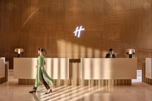 a woman walking past a reception desk in a lobby at Holiday Inn Resort Ho Tram Beach by IHG in Ho Tram