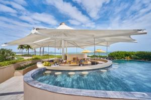 a pool at a resort with a large white umbrella at Holiday Inn Resort Ho Tram Beach, an IHG Hotel in Ho Tram