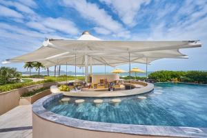 a pool at a resort with a large white umbrella at Holiday Inn Resort Ho Tram Beach by IHG in Ho Tram