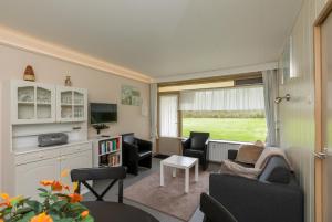 a living room with a couch and chairs and a tv at Burg. Van Woelderenlaan 100-2 in Vlissingen