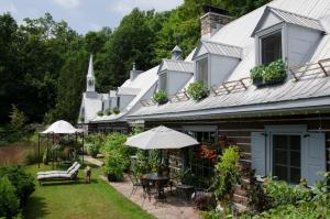 a house with a patio and a church at Le Petit Clocher Gite Touristique B & B in Saint-Sauveur-des-Monts