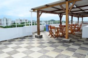 eine Terrasse mit einem Tisch und Stühlen auf dem Dach in der Unterkunft Aparta Hotel Jardines del Caney in Cali