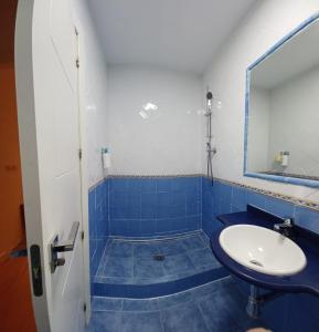 Baño de azulejos azules con lavabo y espejo en Reyno de Baeza, en Baeza