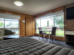 a bedroom with a bed and a table with chairs at Country Roads Motor Inn Naracoorte in Naracoorte