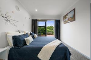 1 dormitorio con 1 cama grande con manta azul en Orange Blossom Cottage - Greytown Holiday Home, en Greytown
