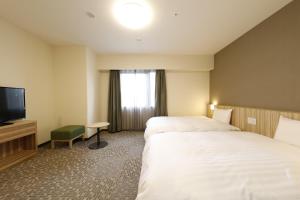 um quarto de hotel com duas camas e uma televisão de ecrã plano em Dormy Inn Maebashi em Maebashi