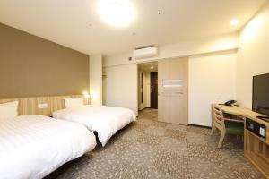 una camera d'albergo con due letti e una televisione di Dormy Inn Maebashi a Maebashi