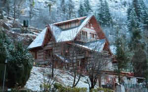 a large wooden house with snow on it at SaffronStays The Amlyn, Manali - unobstructed views of Beas river and the Himalayas in Manāli