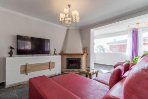 ein Wohnzimmer mit einem roten Sofa und einem TV in der Unterkunft Villa Galicia in Calpe