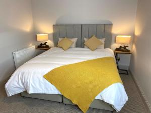 a bedroom with a bed with a yellow blanket on it at The Old Toll House in St. Andrews