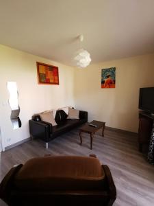 ein Wohnzimmer mit Sofa und Tisch in der Unterkunft Petite maisonnette de plein pied in Le Taillan-Médoc