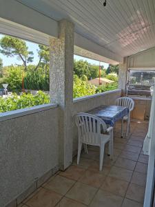 eine Veranda mit 2 Stühlen, einem Tisch und 2 Fenstern in der Unterkunft Petite maisonnette de plein pied in Le Taillan-Médoc + 22 Fotos