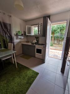 eine Küche mit einem Herd, einem Tisch und einem Fenster in der Unterkunft Petite maisonnette de plein pied in Le Taillan-Médoc
