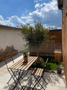a wooden picnic table and two chairs in a backyard at Le Studio de l'Olivier in Courcelles-sur-Seine